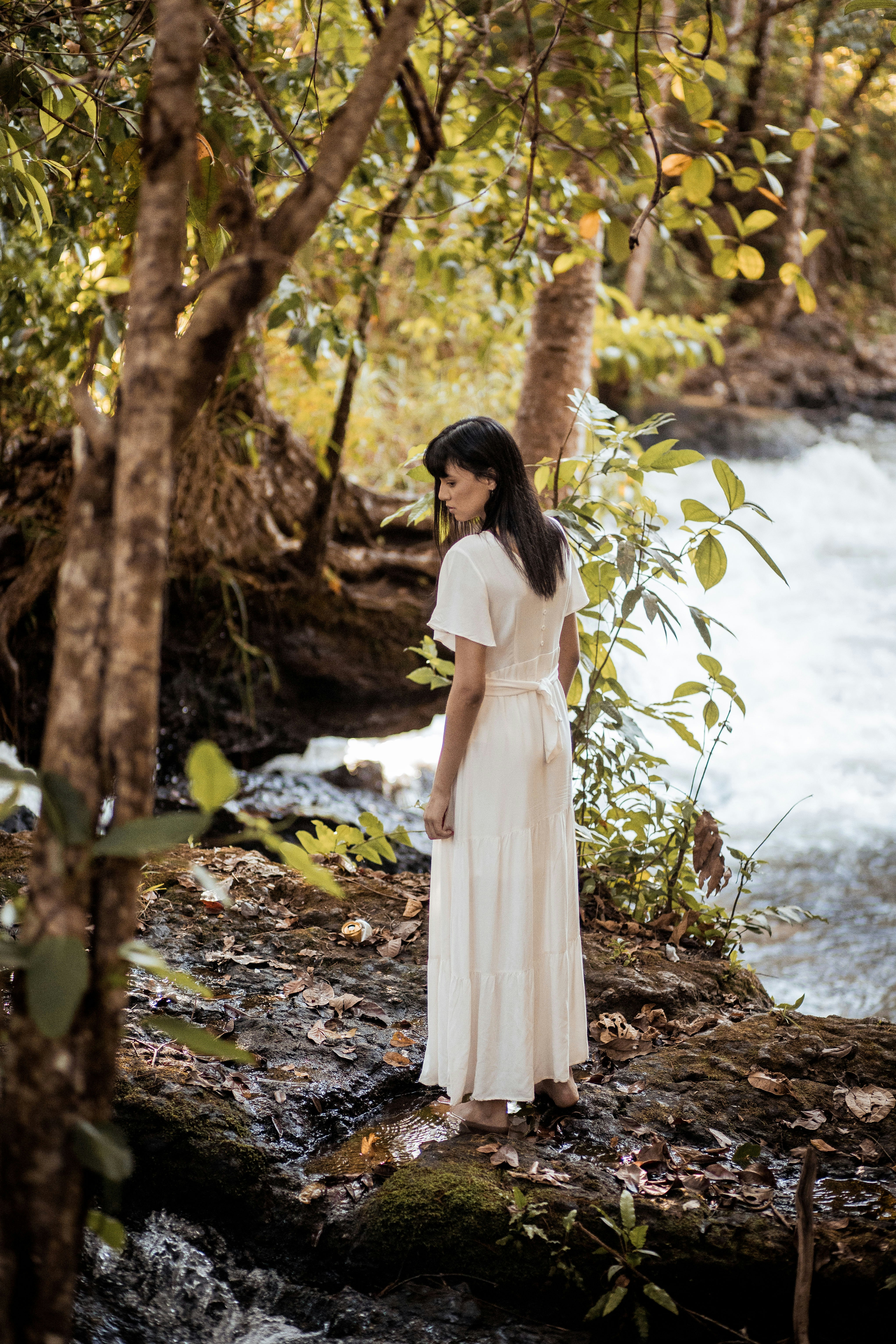 woman in white dress standing near body of water during daytime